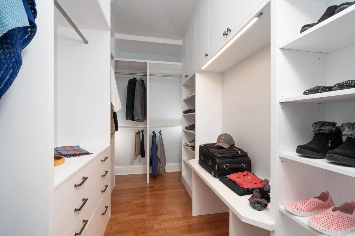 Custom closet with packing bench and drawers for storage in Charlotte, NC by Distinctive Design + Build + Remodel.