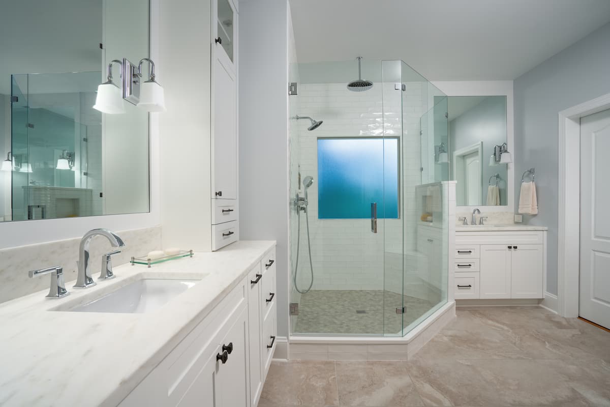 Master bathroom remodel with white cabinets and quartz countertops in Charlotte, NC by Distinctive Design + Build + Remodel.