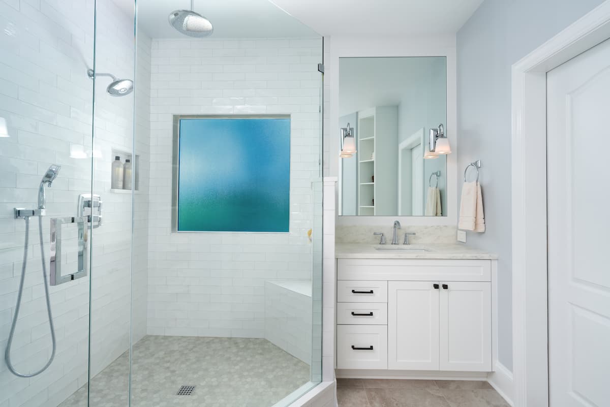 Primary bathroom remodel in Charlotte, NC with large shower, dual vanities and framed mirrors by Distinctive Design + Build + Remodel.