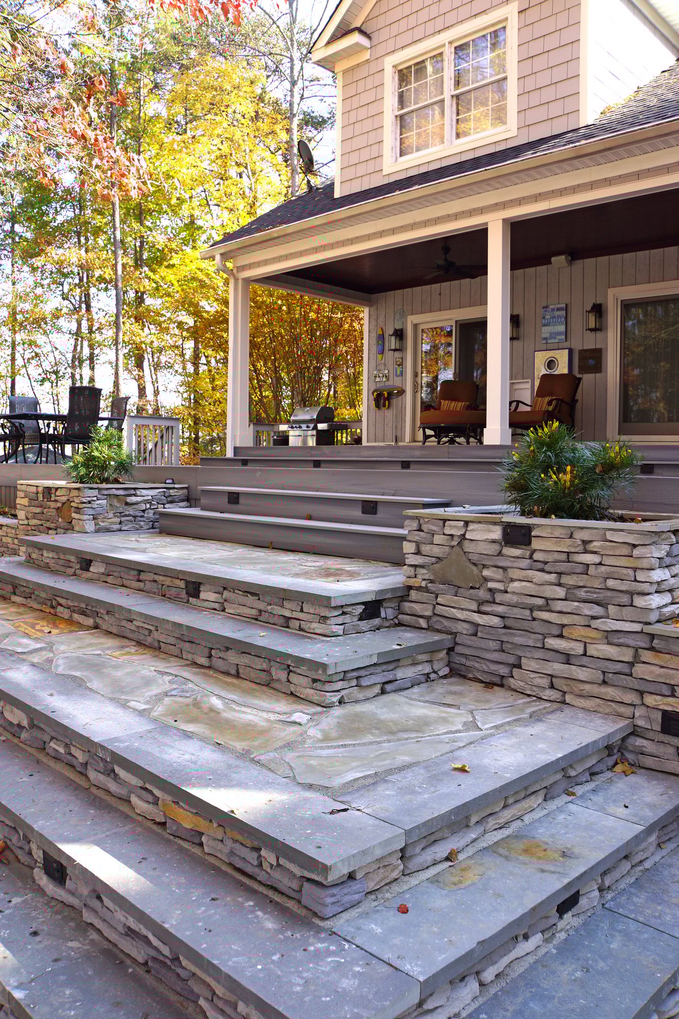 Composite deck with stone planters, retaining walls and landscape lighting by Distinctive Design + Build + Remodel on Lake Norman.
