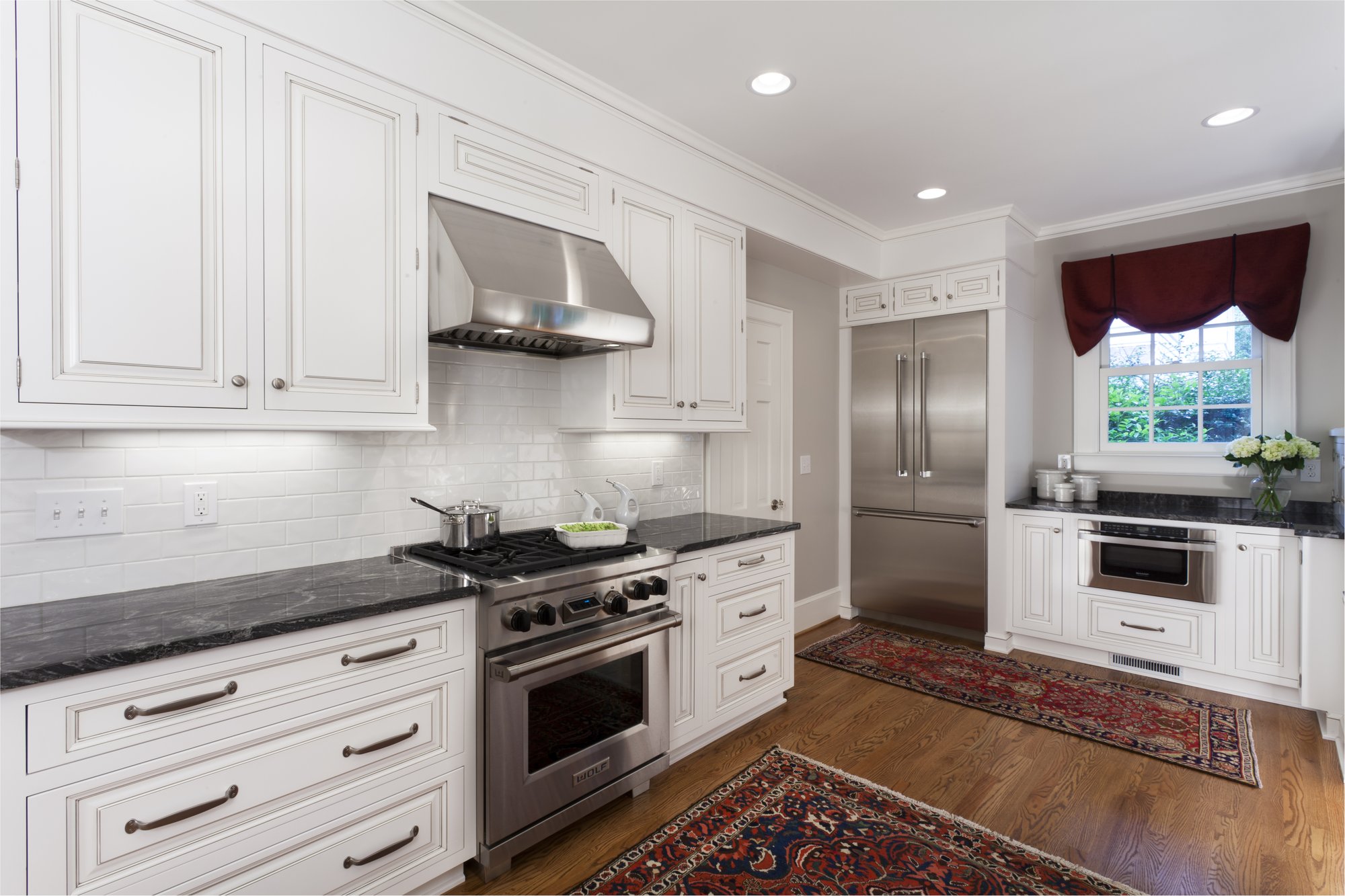 Traditional kitchen remodel in Myers Park with Wolf dual-fuel range, Thermador refrigerator, white cabinetry and black granite countertops by Distinctive Design + Build + Remodel.