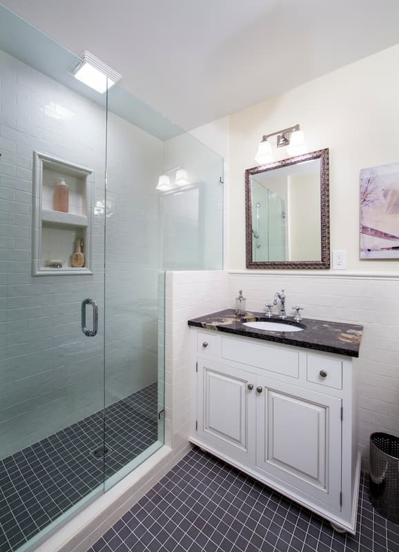 Hall bath remodel in Myers Park by Distinctive Design + Build + Remodel with expansive shower, white cabinetry and tile wainscoting.
