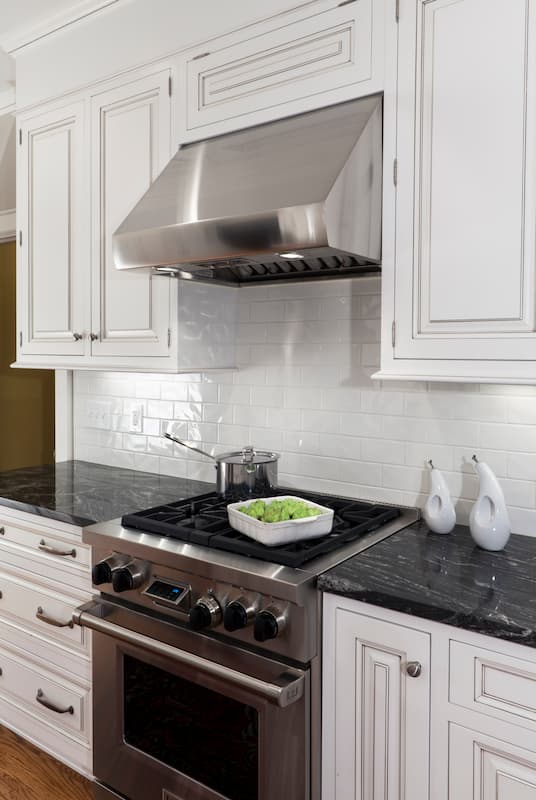 Wolf dual-fuel range in a remodeled kitchen with black countertops in Charlotte, NC by Distinctive Design + Build + Remodel.