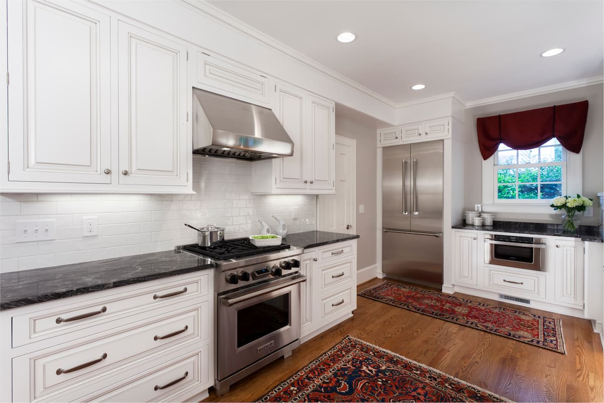 Traditional kitchen remodel in Myers Park with Wolf dual-fuel range, Thermador refrigerator, white cabinetry and black granite countertops by Distinctive Design + Build + Remodel.