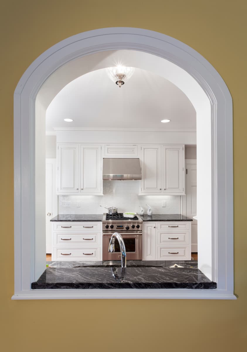 An arched pass-thru in a kitchen in Myers Park by Distinctive Design + Build + Remodel