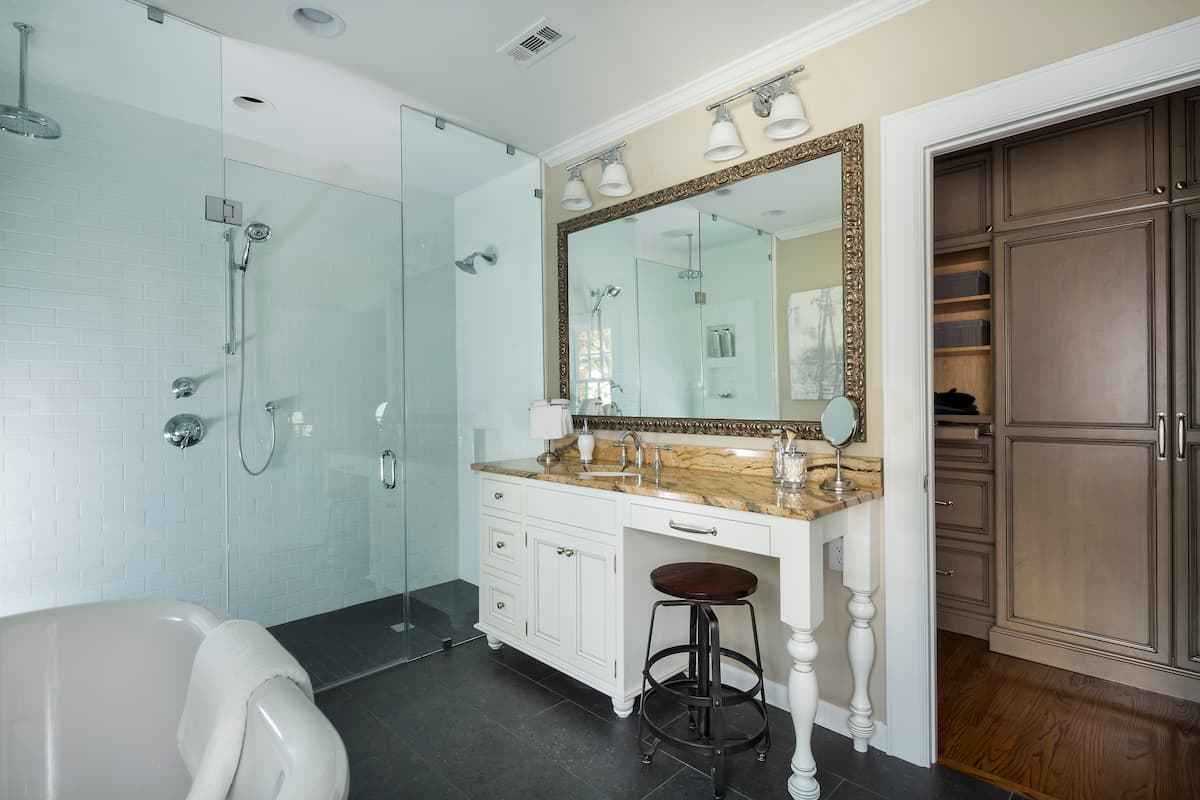 Primary bathroom remodel with expansive barrier-free shower, custom cabinetry and a free-standing tub in Myers Park by Distinctive Design + Build + Remodel.