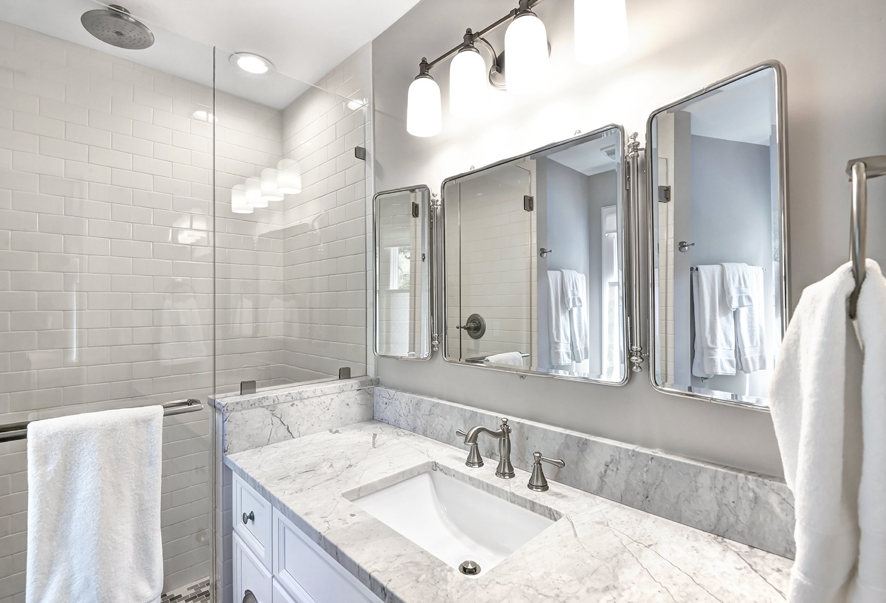 White and gray bathroom remodel with Carrara marble countertops and brushed nickel hardware on Kiawah Island, SC by Distinctive Design + Build + Remodel.