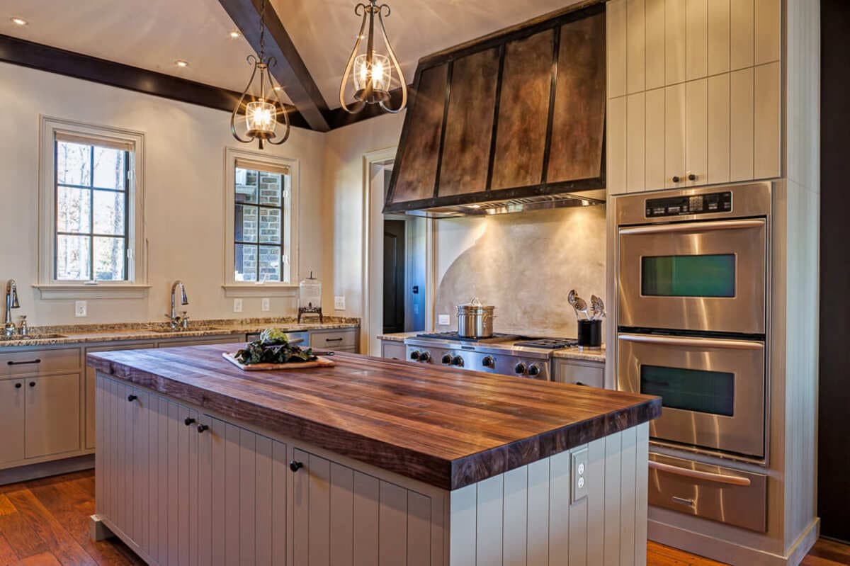 Venetian marble backsplash and custom metal vent hood in a kitchen remodeled by Distinctive Design + Build + Remodel on Lake Norman, NC.