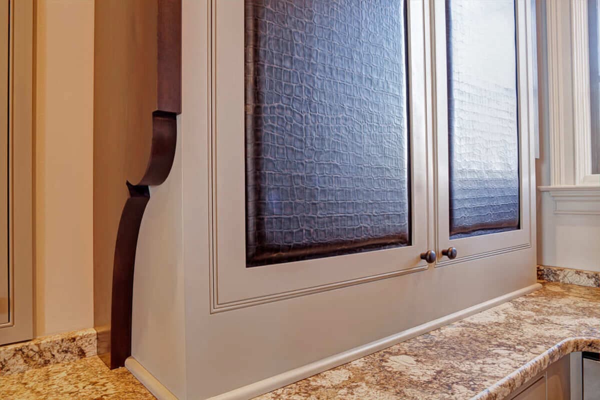 Leather cabinet door panel in a Lake Norman kitchen remodel by Distinctive Design + Build + Remodel.