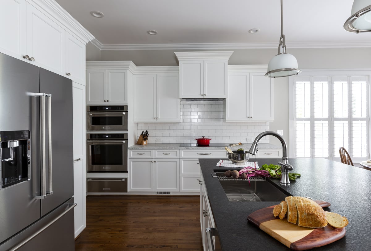 Kitchen in Belmont, NC is transformed by Distinctive Design + Build + Remodel with crisp white cabinetry and subway tile, black leathered granite and stainless-steel appliances.