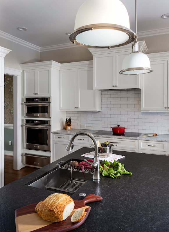Kitchen in Belmont, NC remodeled with crisp white cabinetry and subway tile, black leathered granite countertops and stainless-steel appliances.