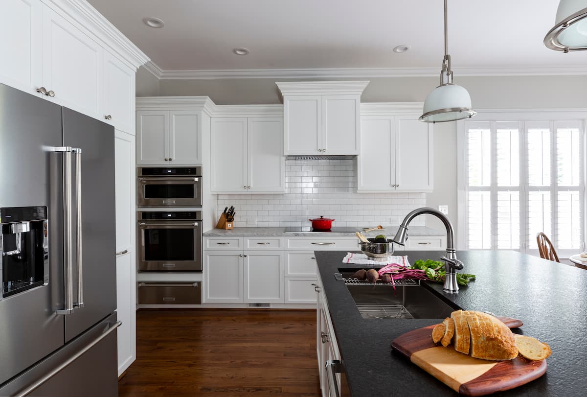 Kitchen in Belmont, NC is transformed by Distinctive Design + Build + Remodel with crisp white cabinetry and subway tile, black leathered granite and stainless-steel appliances.
