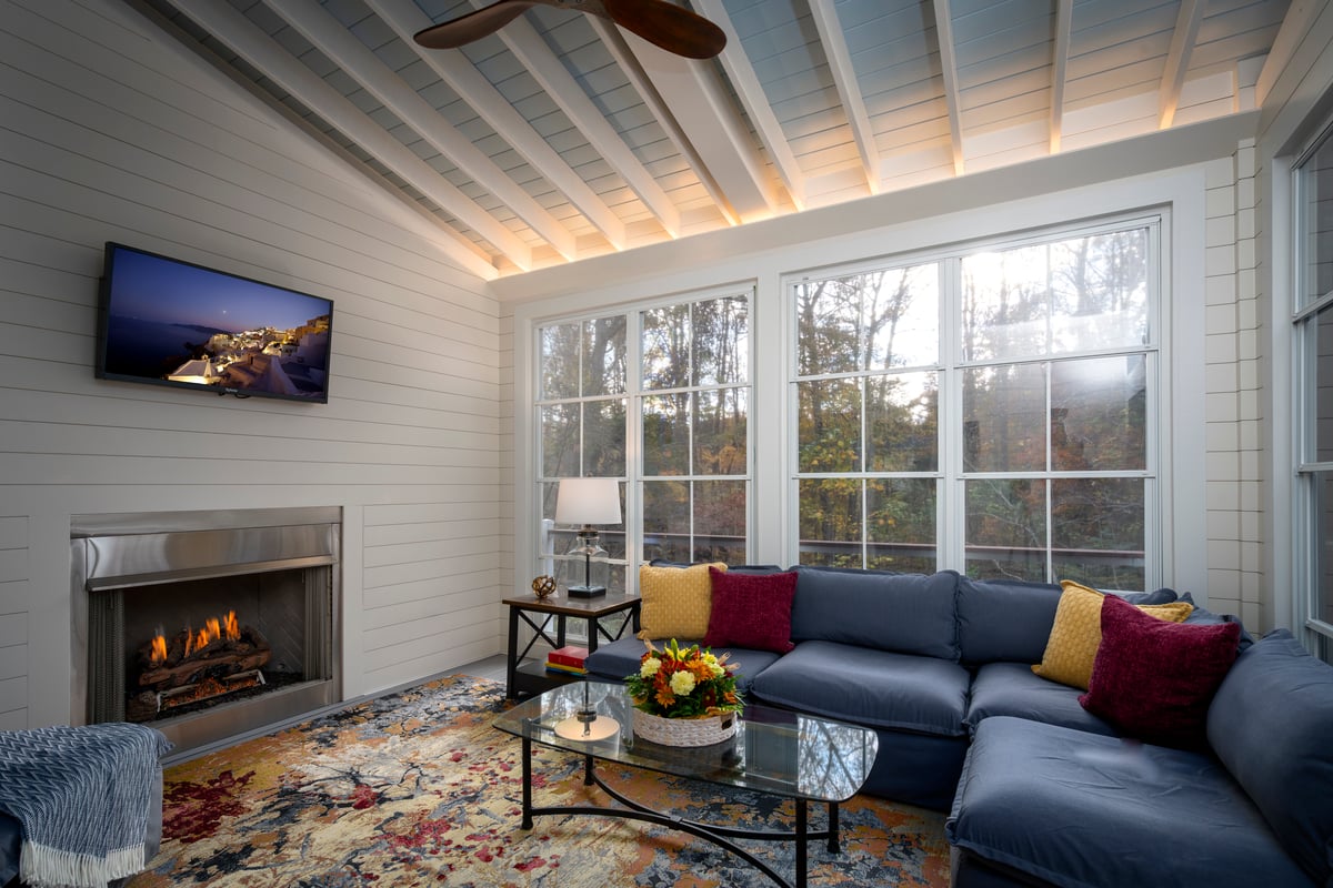 Sunroom addition in Charlotte, NC with Eze-Breeze windows and gas fireplace by Distinctive Design + Build + Remodel.
