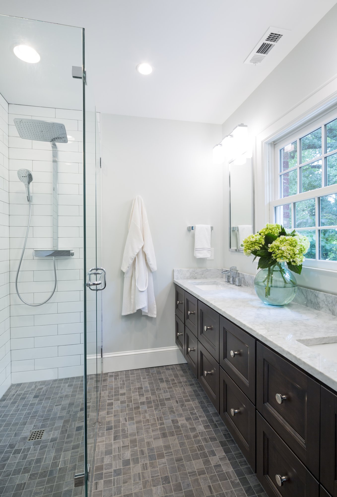 National award-winning primary bathroom remodel in Myers Park by Distinctive Design + Build + Remodel with a barrier-free shower, wall-hung vanity and Hansgrohe shower tower.