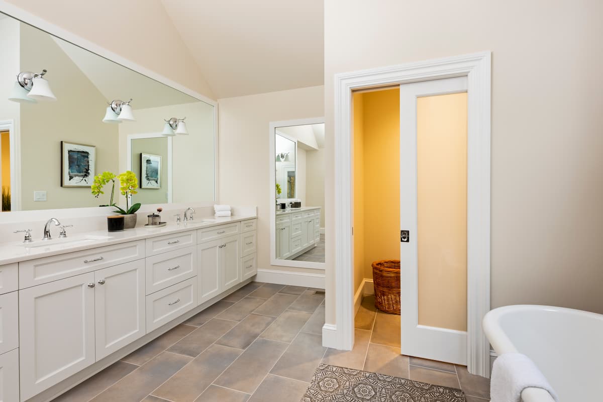Bathroom remodel in Charlotte, NC with custom double vanity, expansive framed mirror and soothing colors by Distinctive Design + Build + Remodel.