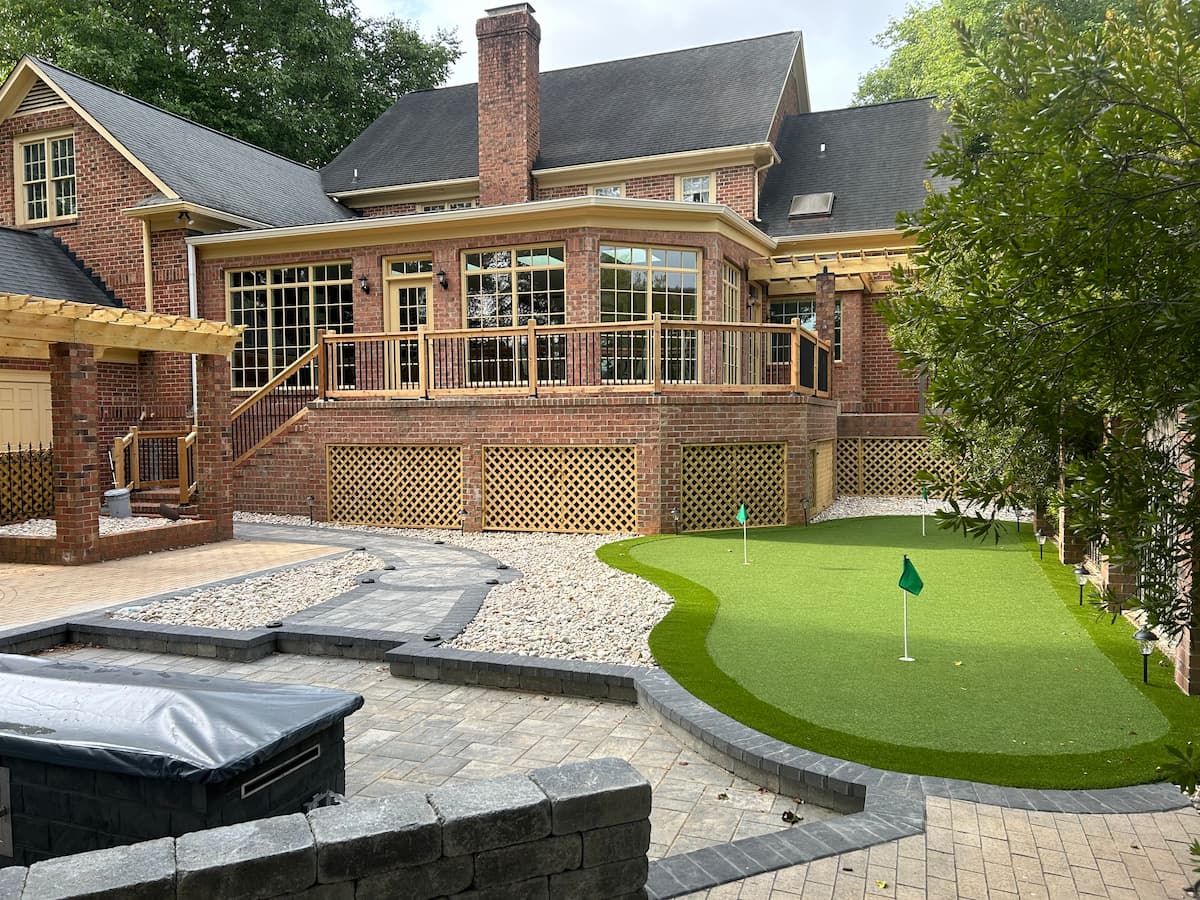 Large sunroom addition with putting green and outdoor fireplace in Cramer Mountain Country Club by Distinctive Design + Build + Remodel.