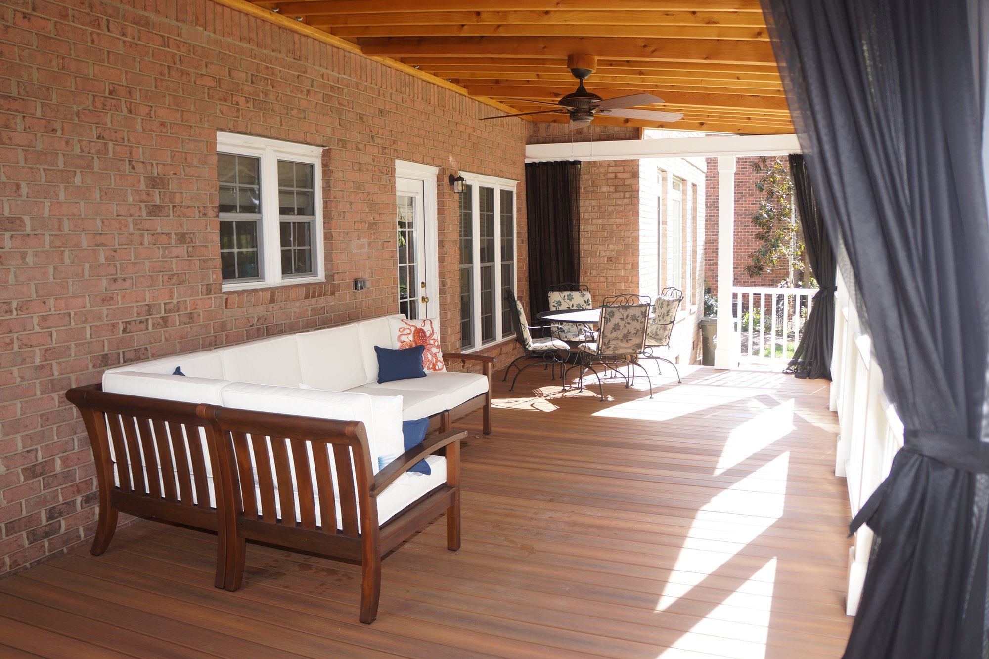 A covered porch addition with Mosquito Curtains in Huntersville, NC by Distinctive Design + Build + Remodel.
