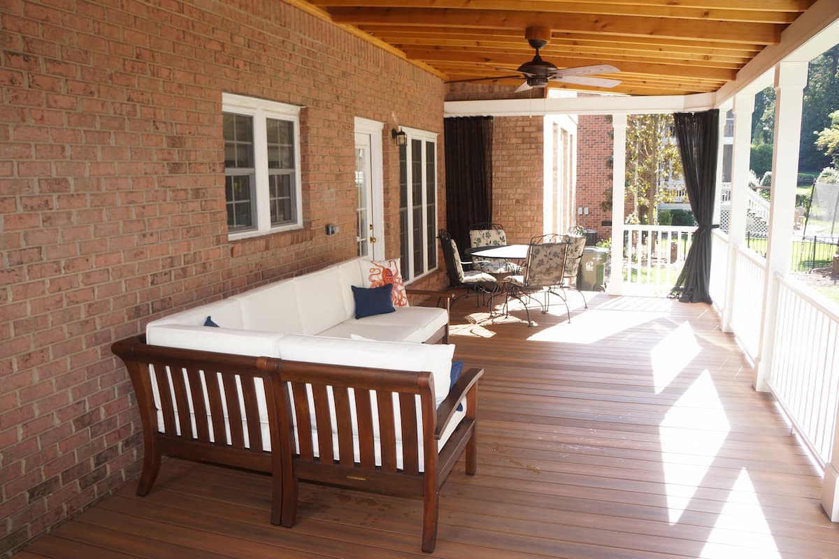 A covered porch addition with Mosquito Curtains in Huntersville, NC by Distinctive Design + Build + Remodel.