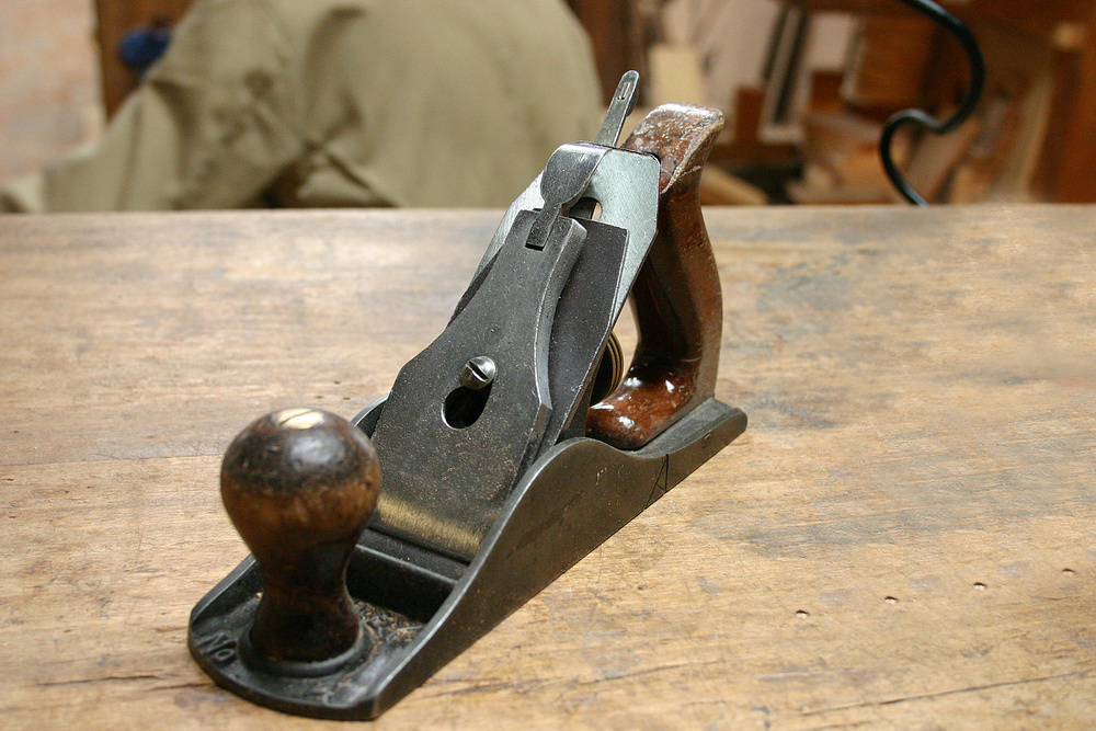 Antique manual carpenter's planer on a wood table.