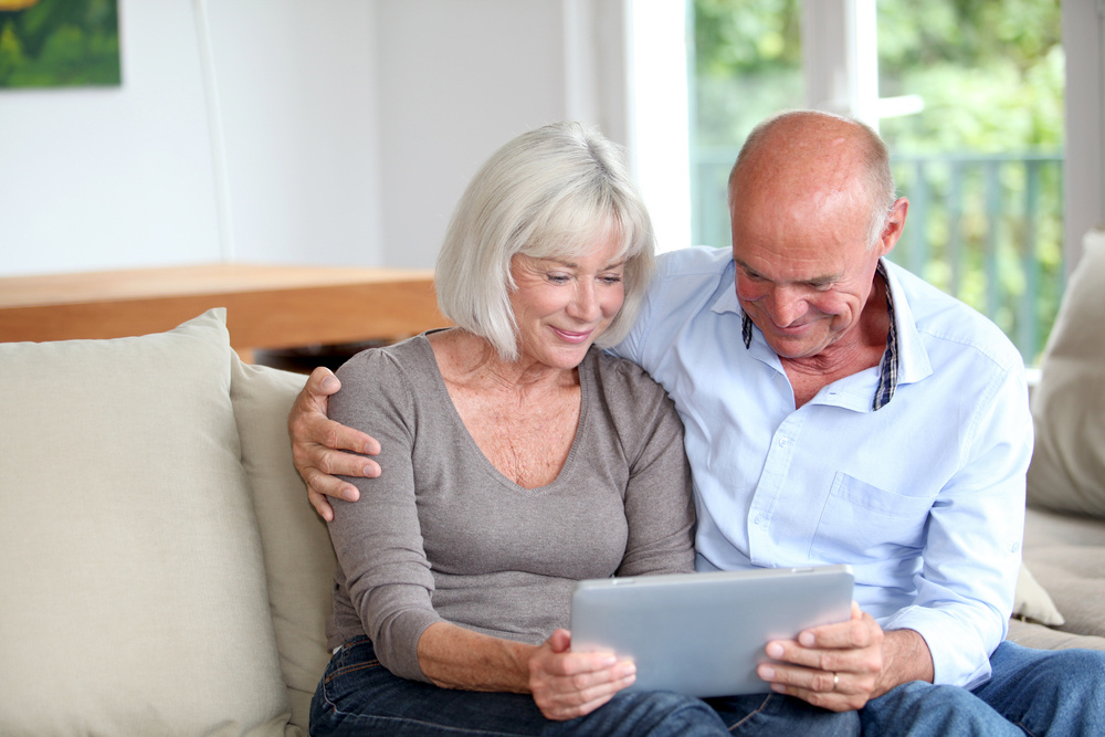 Baby boomer couple looking at a tablet with information about remodeling costs in Charlotte, NC.