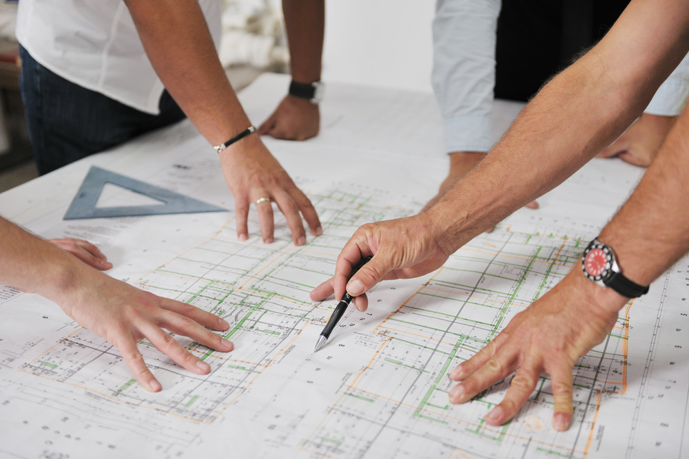 An architect, designer and builder from Distinctive Design + Build + Remodel working together on a construction drawing in Charlotte, NC.