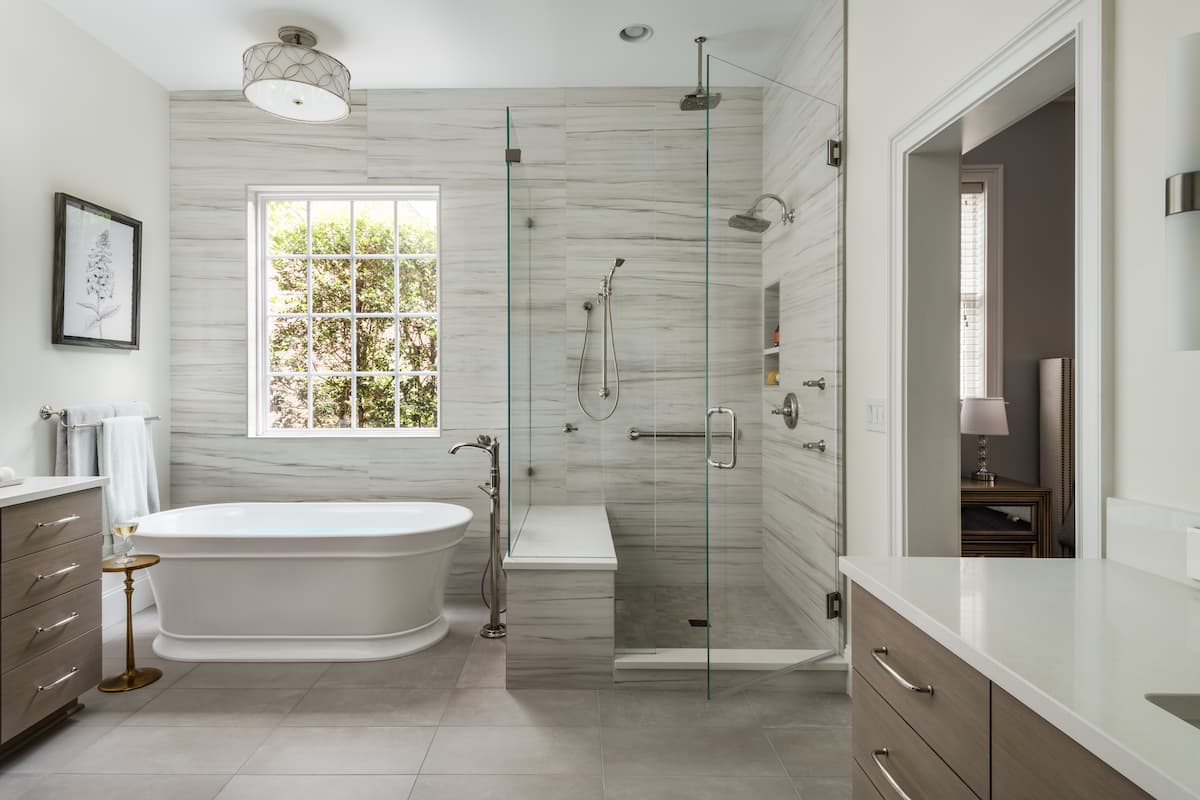 Tile feature wall, shower, and free-standing tub in a master bathroom remodeled by Distinctive Design + Build + Remodel in Charlotte, NC.