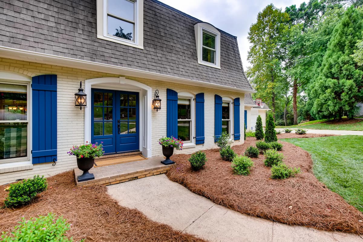 Stunning whole house remodel front entry with blue shutters in Charlotte, NC by Distinctive Design + Build + Remodel.